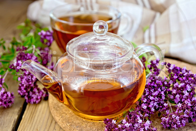 Tea of oregano in glass teapot on board with cup