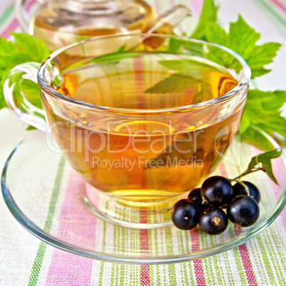 Tea with blackcurrants in cup on tablecloth