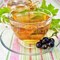 Tea with blackcurrants in cup on tablecloth