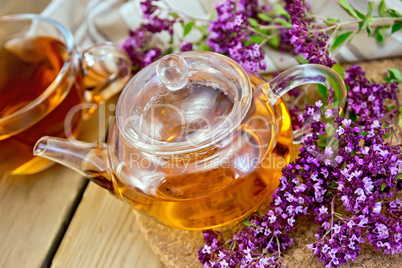 Tea of oregano in glass teapot on board