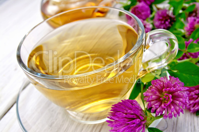 Tea with clover in cup on light board