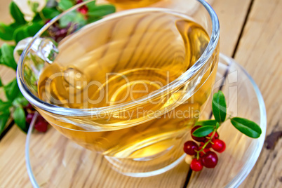 Tea with lingonberry in glass cup on board