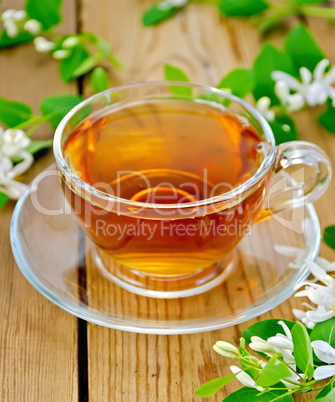 Tea with white flowers of honeysuckle on board