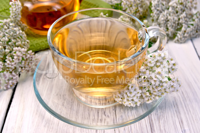 Tea with yarrow in glass cup on light board
