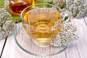 Tea with yarrow in glass cup on light board