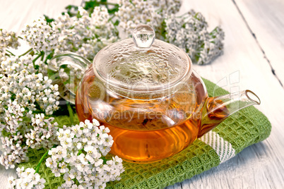 Tea with yarrow in glass teapot on napkin
