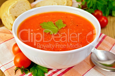 Tomato soup in bowl on napkin with bread