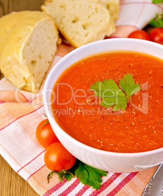 Tomato soup in bowl with bread on napkin