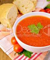 Tomato soup in bowl with bread on napkin
