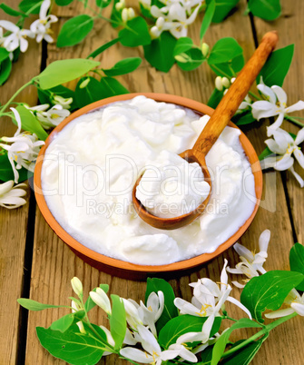 Yogurt in clay bowl with spoon and flowers of honeysuckle