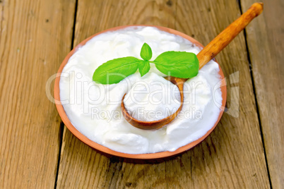 Yogurt in clay bowl with spoon on board