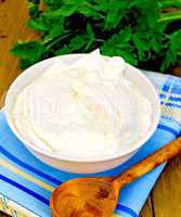 Yogurt in white bowl with greens on board