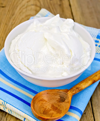 Yogurt in white bowl with spoon on board