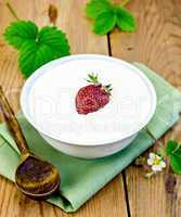 Yogurt thick with strawberries in bowl on board