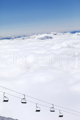 Chair-lift and mountains under clouds in sun day