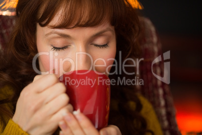 Redhead with eyes closed drinking hot drink