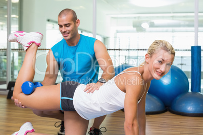 Trainer assisting woman with exercises at fitness studio