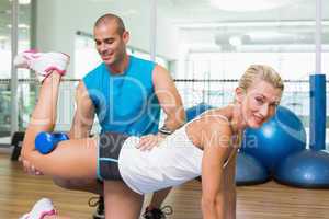 Trainer assisting woman with exercises at fitness studio