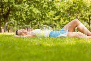 Happy fit brunette lying and relaxing on the grass