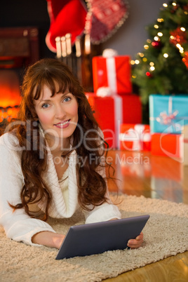 Redhead woman lying on floor using tablet at christmas