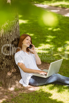 Pretty redhead on the phone holding her laptop