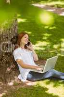 Pretty redhead on the phone holding her laptop