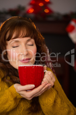 Pretty redhead enjoying hot drink at christmas
