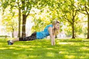 Fit blonde doing push ups in the park