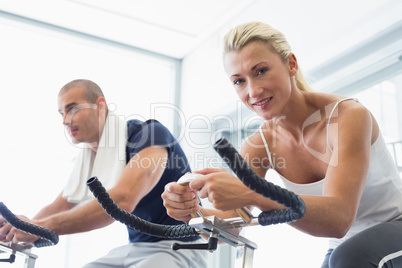 Fit couple working on exercise bikes at gym