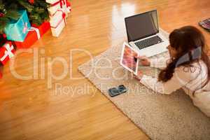 Pretty woman lying on floor using technology at Chritmas