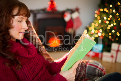 Beautiful redhead reading on the couch at christmas