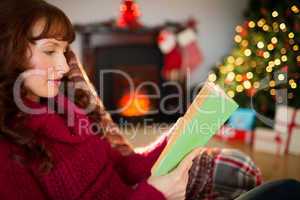 Beautiful redhead reading on the couch at christmas