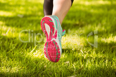 Woman in running shoes running on grass