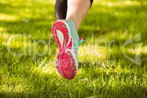 Woman in running shoes running on grass
