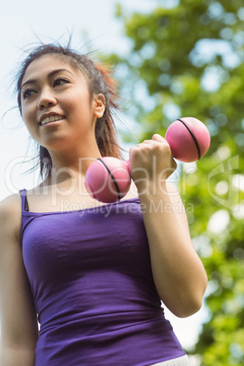 Healthy woman lifting dumbbells in park