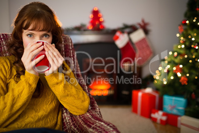 Cheerful redhead drinking hot drink at christmas