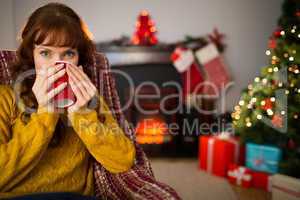 Cheerful redhead drinking hot drink at christmas