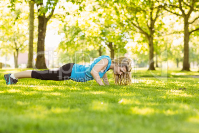 Fit blonde doing push ups in the park