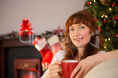 Smiling redhead holding a mug of hot drink at christmas