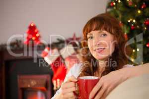 Smiling redhead holding a mug of hot drink at christmas