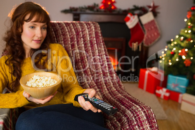 Pretty redhead watching television on couch at christmas