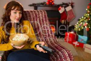 Pretty redhead watching television on couch at christmas