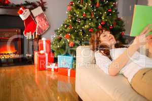 Cheerful redhead reading on the couch at christmas