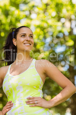 Smiling brunette in sportswear with her hands on hips