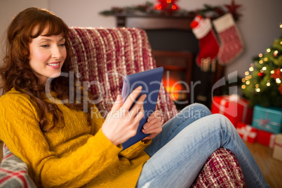 Redhead woman sitting on couch using tablet at christmas