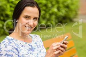 Smiling brunette using her smartphone