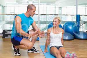 Trainer assisting woman with exercises at fitness studio