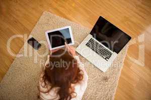 Pretty woman lying on floor using technology at Chritmas