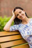 Smiling brunette sitting on bench looking at camera
