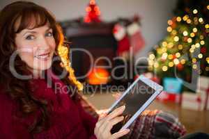 Cheerful redhead using tablet at christmas